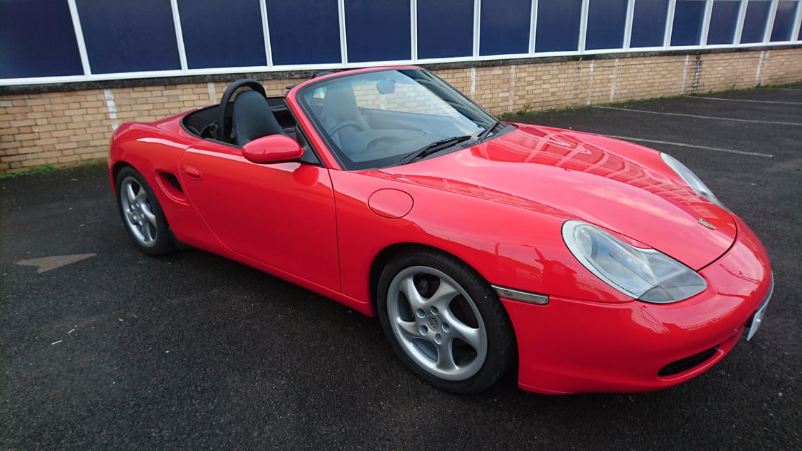 a red porsche sports car parked in front of a building in cardiff for car body repair near me in south wales